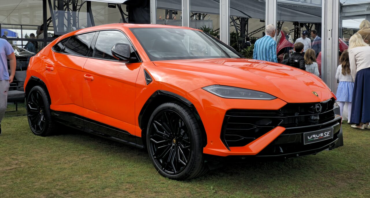 Lamborghini Urus SE laranja sobre a grama, com visitantes ao fundo